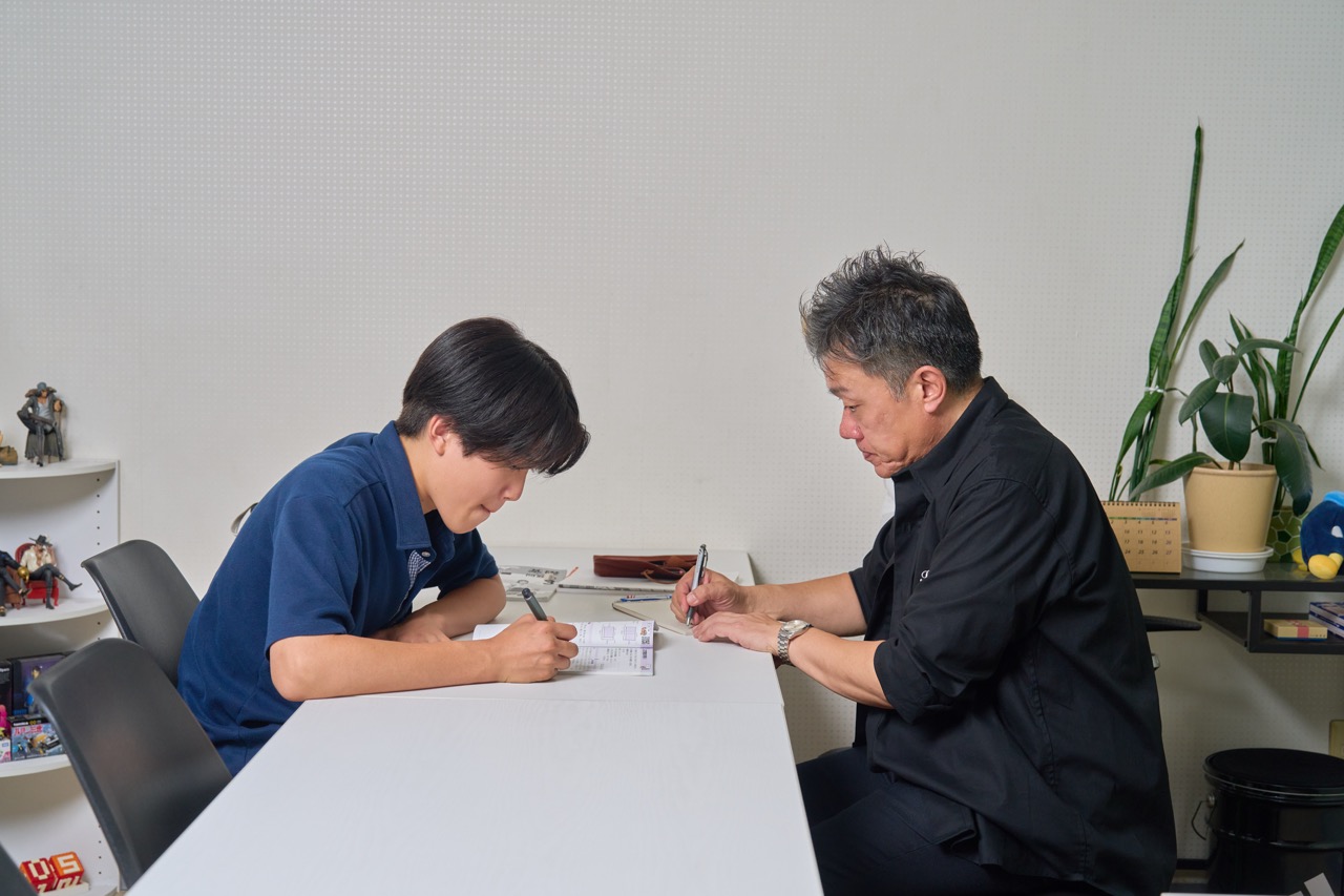 生徒が問題を解き、塾長がそばで確認している様子